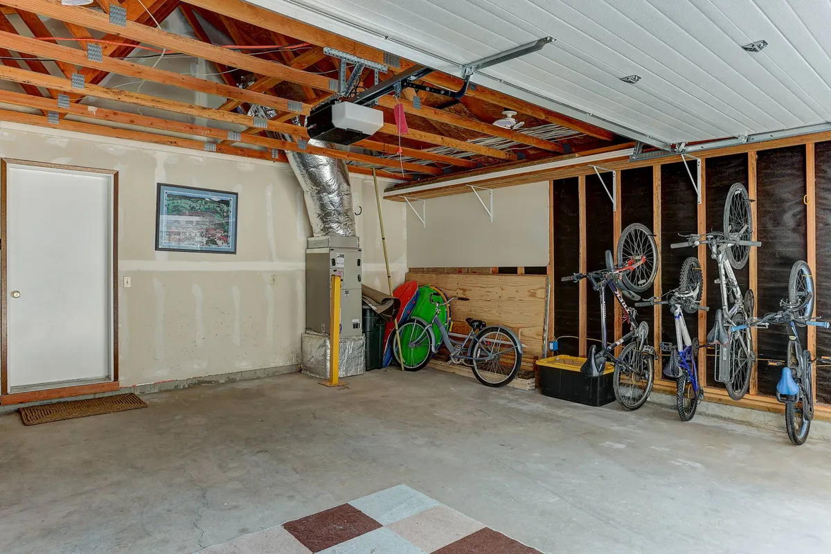 A practical, well-lit garage with bikes mounted on the wall, organized storage shelves, and a door leading outside. The space is clearly designed for stowing outdoor equipment and prepping gear for any adventure.
