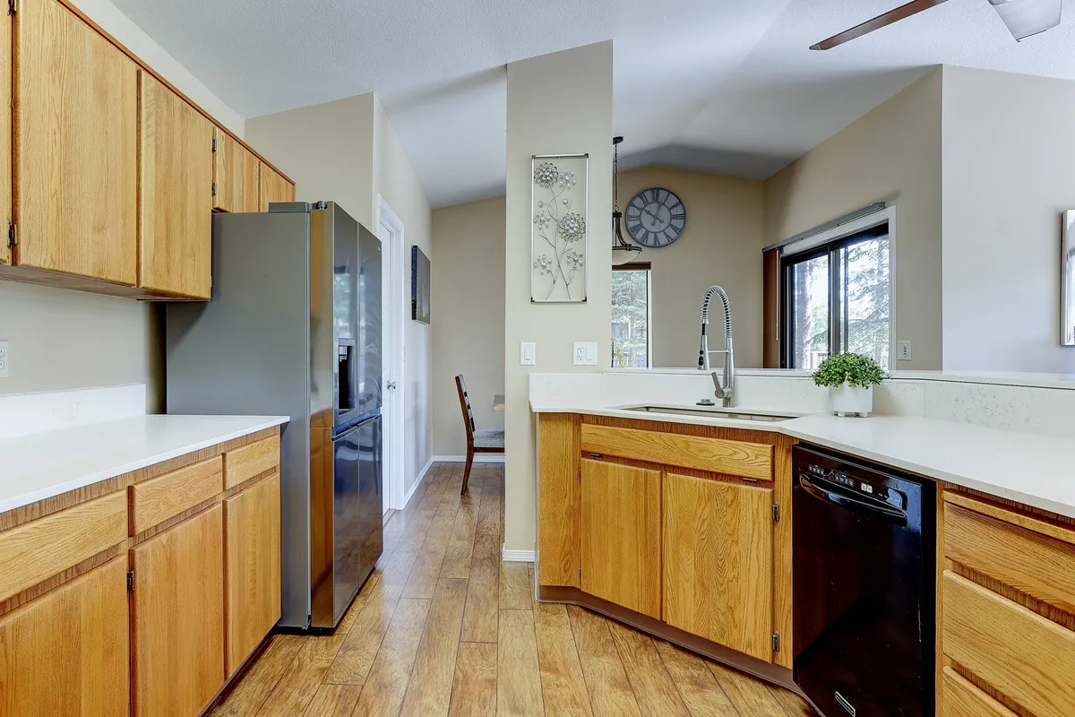 An inviting kitchen with a prominent kitchen island, stainless steel appliances, and a window letting in natural light. Decorative touches and a hint of the adjacent dining area suggest a seamless flow between cooking and gathering spaces.