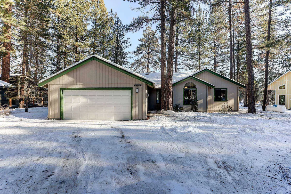 The home's inviting facade is surrounded by snow-covered ground and framed by tall pine trees. The tranquil exterior setting evokes a sense of peaceful retreat, perfect for family gatherings and seasonal outdoor activities.